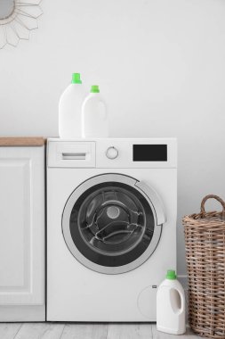 Çamaşır odasında deterjan şişeleri olan modern çamaşır makinesi.