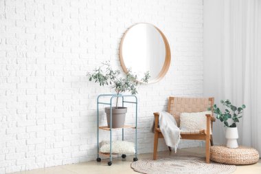 Ayna, koltuk ve raf üniteli aydınlık oturma odasının içinde.