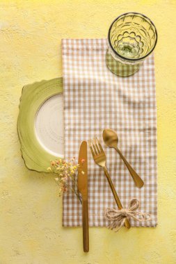Table setting with flower decor on yellow background