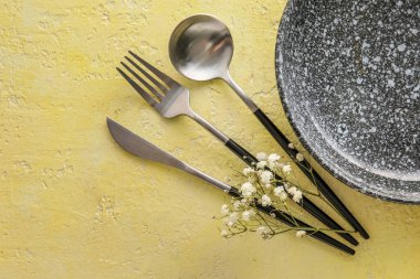 Table setting with plate and cutlery on yellow background