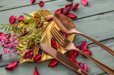Renkli ahşap arka planda şık çatal bıçak takımı ve çiçek dekoru olan masa ayarları