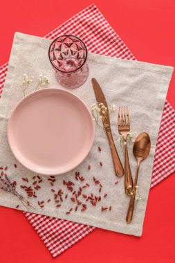 Table setting with gypsophila flowers and dry seeds on red background