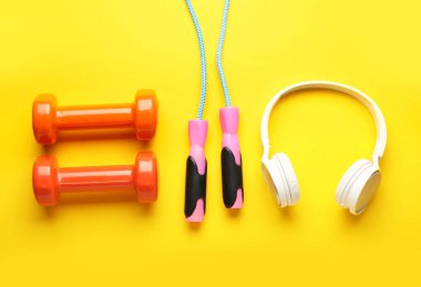 Dambıllar, ip atlama ve sarı arka planda modern kulaklıklar.