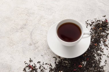 Bir fincan siyah çay ve açık arkaplanda kurumuş yapraklar.