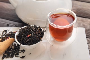 Ahşap zemin üzerinde cam çay ve kurumuş yapraklar olan tahta pano, yakın plan.