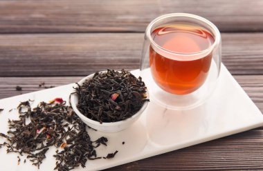 Ahşap zemin üzerinde cam çay ve kurumuş yapraklar olan tahta pano, yakın plan.