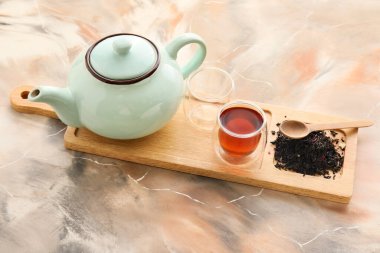 Ahşap tahta, bir fincan siyah çay, çaydanlık ve arkaplanda kurumuş yapraklar.