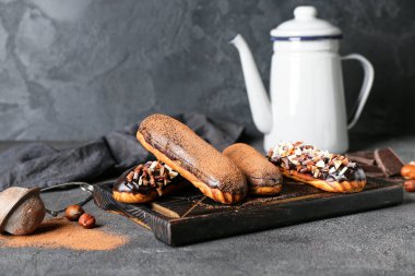 Koyu arkaplanda lezzetli çikolata ekleri olan ahşap tahta tahta.