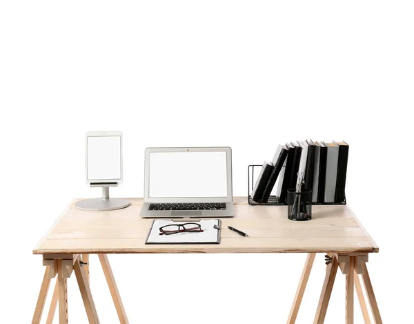 Wooden standing desk with laptop, tablet computer, notebooks, clipboard and eyeglasses on white background, closeup