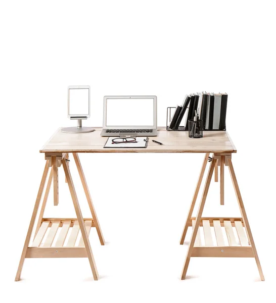 Wooden standing desk with laptop, tablet computer, notebooks, clipboard and eyeglasses on white background