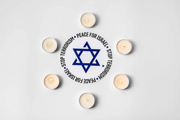 Burning candles, card with star of David and text STOP TERRORISM and PEACE FOR ISRAEL