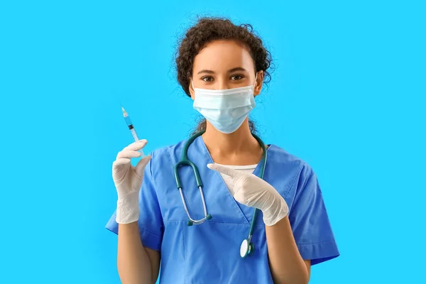 Female Doctor Medical Mask Pointing Syringe Blue Background — Stock Photo, Image