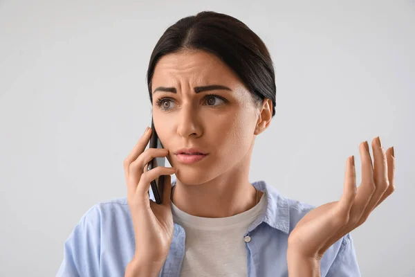 Mujer Joven Estresada Hablando Por Teléfono Móvil Sobre Fondo Claro —  Fotos de Stock
