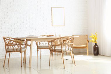 Beyaz tuğla duvarın yanındaki modern mobilyalarla yemek odasının içinde.