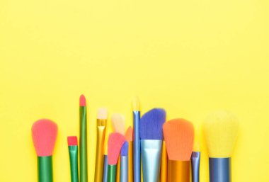 Sarı arkaplanda makyaj fırçaları
