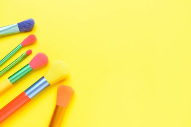 Sarı arkaplanda farklı makyaj fırçaları