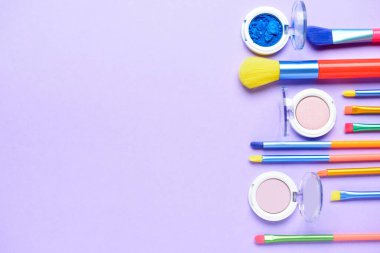 Renk arkaplanındaki makyaj fırçaları ve göz falı setleri