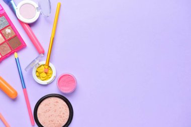 Renkli arka planda makyaj fırçaları ve farklı dekoratif kozmetikler