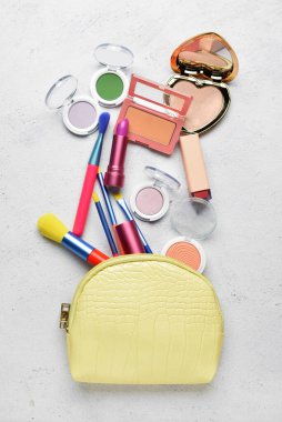 Açık arkaplanda fırçalar ve dekoratif kozmetik ürünler bulunan makyaj çantası