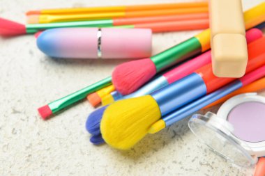 Farklı dekoratif kozmetik ürünleri ve hafif arka planda fırçalar, yakın plan