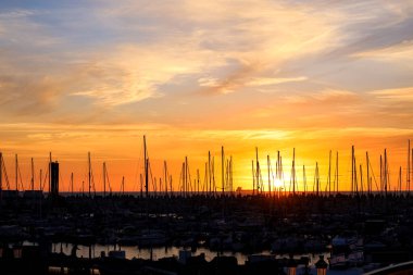 Günbatımında direkleri gökyüzü arkaplanına dayanan yatlar