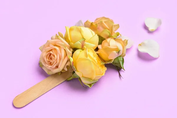 Beautiful roses and ice cream stick on color background