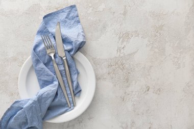 Açık arkaplanda mavi peçete ve çatal bıçak takımı olan masa ayarları