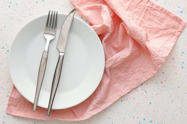 Tabakta çatal bıçak takımı ve arka planda pembe peçete.