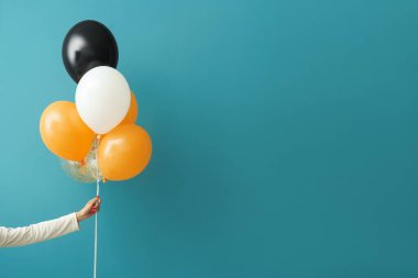 Renkli duvarın yanında Cadılar Bayramı balonları olan kadın.