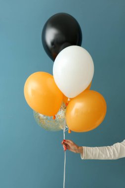 Renkli duvarın yanında Cadılar Bayramı balonları olan kadın.