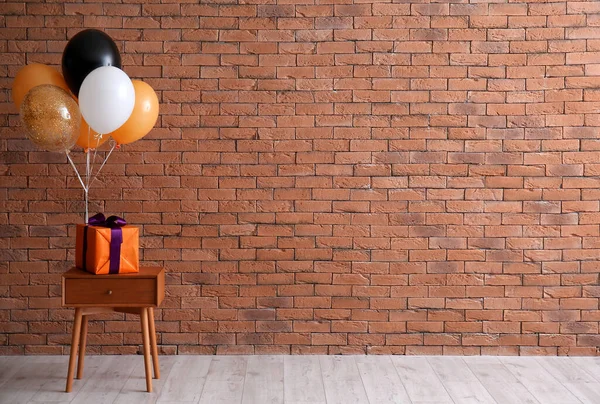 Stolik Pudełkiem Prezentów Balony Halloween Pobliżu Ściany Cegły — Zdjęcie stockowe
