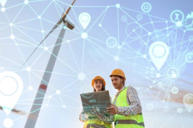 Elektrik üretimi için yel değirmeni çiftliğinde dizüstü bilgisayarı olan mühendisler.