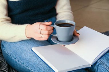 Kitaplı ve kahveli kadın, yakın plan.