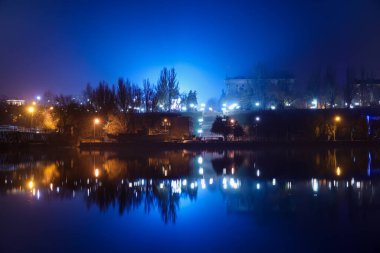 Geceleri parlayan ışıkları olan güzel bir nehir ve şehir manzarası.