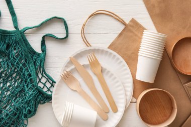 Beyaz ahşap arka planda farklı çantalar ve eko sofra takımı