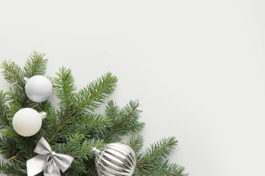 Beyaz arka planda gümüş Noel süslemeleri olan fidan dalları