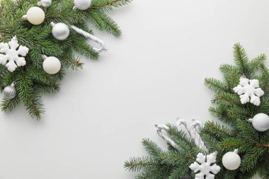 Beyaz arkaplanda köknar dalları ve Noel süslemeleri bulunan kompozisyon