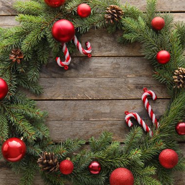 Köknar dallarından yapılmış Noel çelengi ve ahşap arka planda süslemeler, yakın plan.
