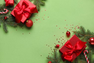 Köknar dalları, Noel hediyeleri ve yeşil arka planda süslemeleri olan kompozisyon
