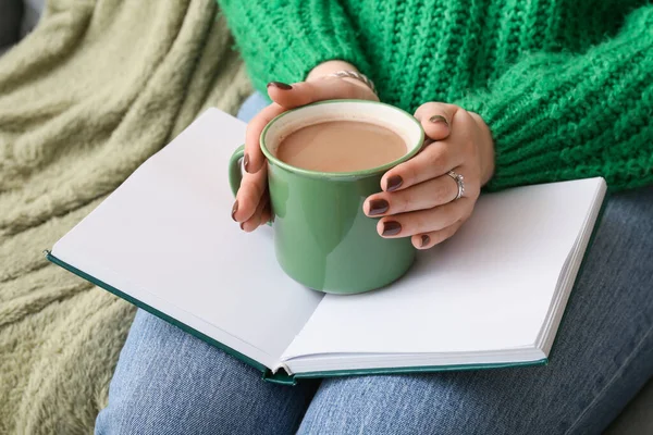 Woman with cup of coffee and book, closeup