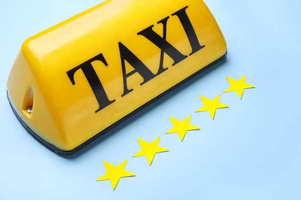 青い背景に黄色のタクシー屋根の看板と紙の星 — ストック写真
