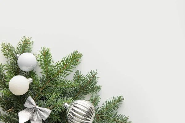 Fir tree branches with silver Christmas decorations on white background