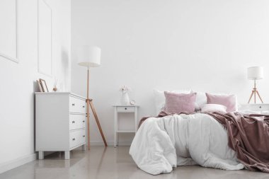 Masaları ve lambaları olan aydınlık yatak odasının içi