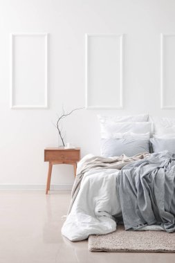 Ağaç dallı vazo, masada kahve fincanı ve ışık duvarının yanında rahat bir yatak.