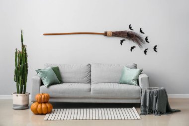 Gri kanepe ve balkabaklarıyla Cadılar Bayramı için dekore edilmiş oturma odasının içi.