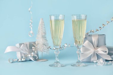 Şampanya kadehleri, Noel hediyeleri ve arka planda yılan yağı.