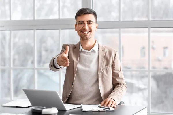 Smiling businessman reaching out for handshake in office