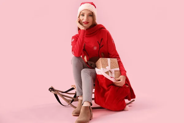 Beautiful Young Woman Santa Hat Bag Gifts Sledge Pink Background — Stock Photo, Image