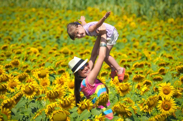 Красивая женщина и ребенок с подсолнухом на весеннем поле — стоковое фото