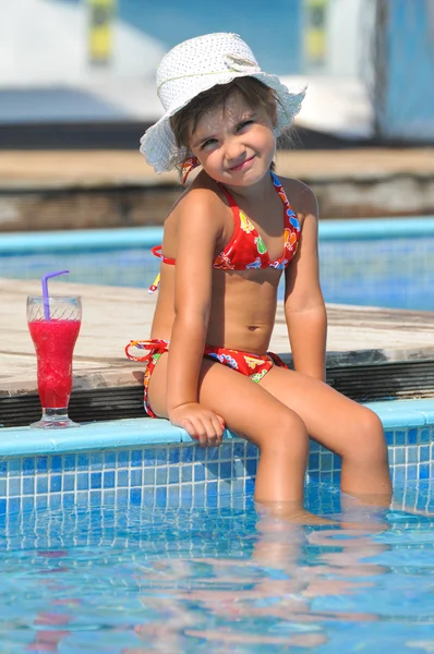 Little girl in the swimming pool with cocktail — Stock Photo, Image